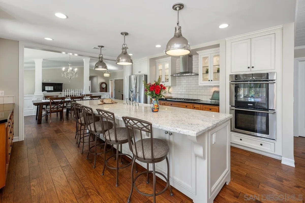 13627 Poway Springs Road Poway, CA 92064 - Photo 10 of 60 a kitchen with stainless steel appliances granite countertop a stove top oven a sink dishwasher a dining table and chairs with wooden floor