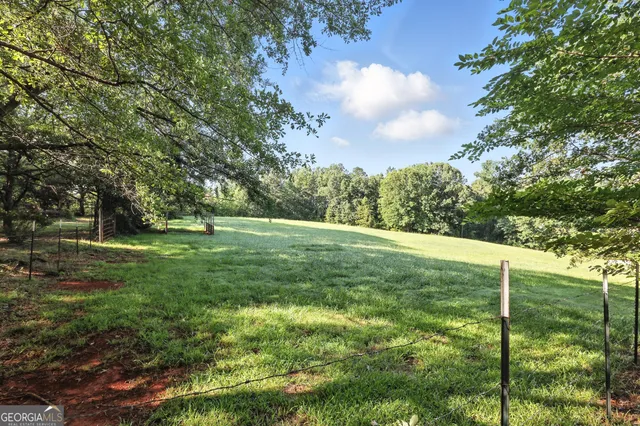a view of a green field with wooden fence