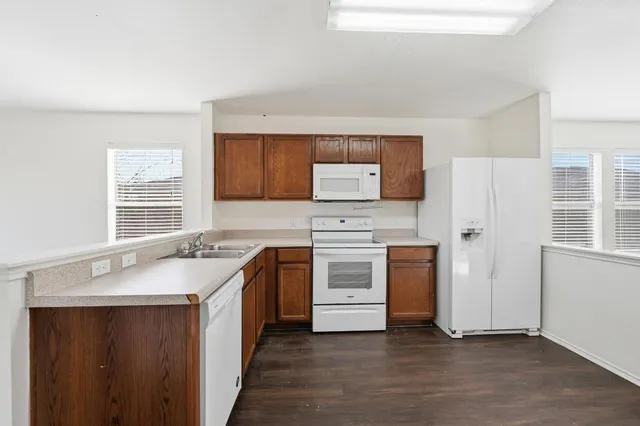 a kitchen with granite countertop a sink stove and refrigerator