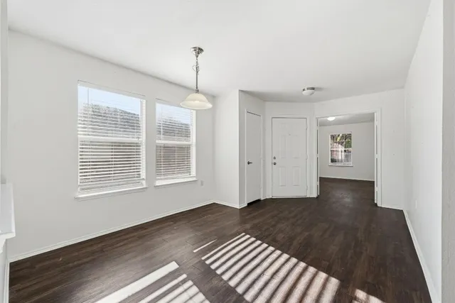 a view of an empty room with a window and wooden floor