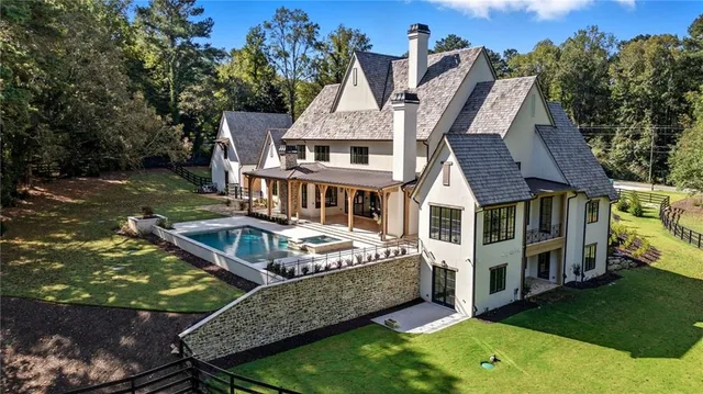 an aerial view of a house with swimming pool next to a yard