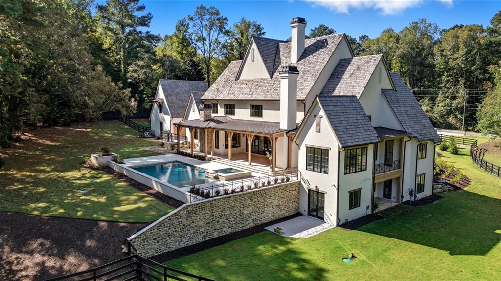 an aerial view of a house with swimming pool next to a yard
