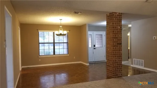 a view of an empty room with window and wooden floor