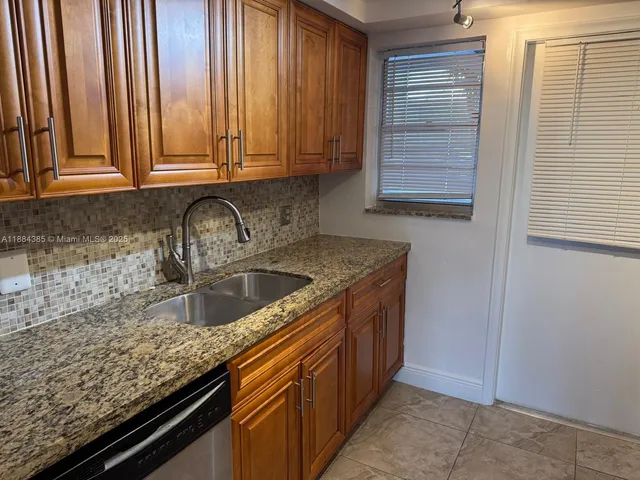 a kitchen with granite countertop a sink and cabinets