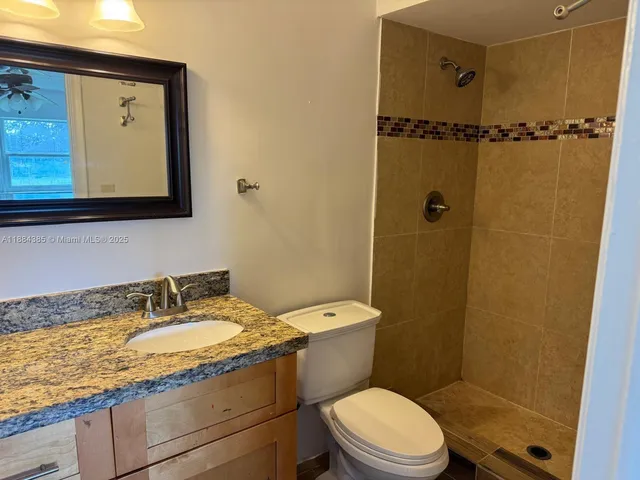 a bathroom with a granite countertop toilet sink and mirror