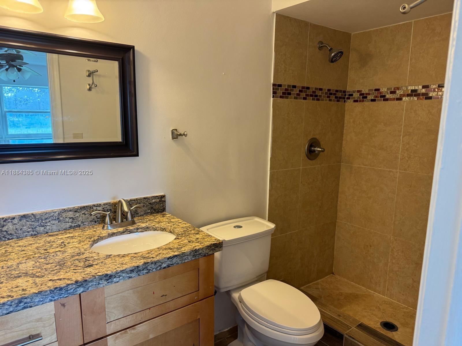 2471 Southwest 82nd Avenue, Unit 108 Davie, FL 33324 - Photo 10 of 14 a bathroom with a granite countertop toilet sink and mirror