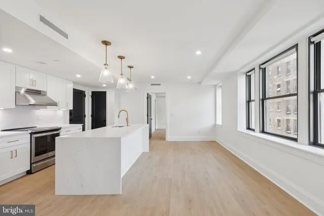 a large kitchen with stainless steel appliances kitchen island a large counter top and a wooden floors