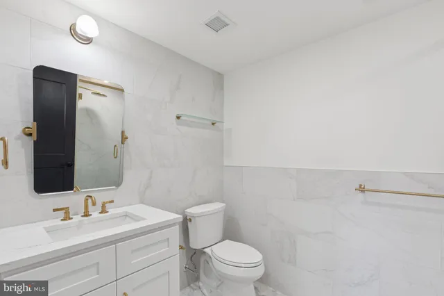 a bathroom with a toilet a sink a vanity and mirror