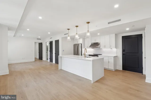 a large white kitchen with kitchen island a sink a center island stainless steel appliances and a cabinets