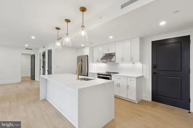 a kitchen with stainless steel appliances kitchen island granite countertop a refrigerator a sink dishwasher a stove with white cabinets