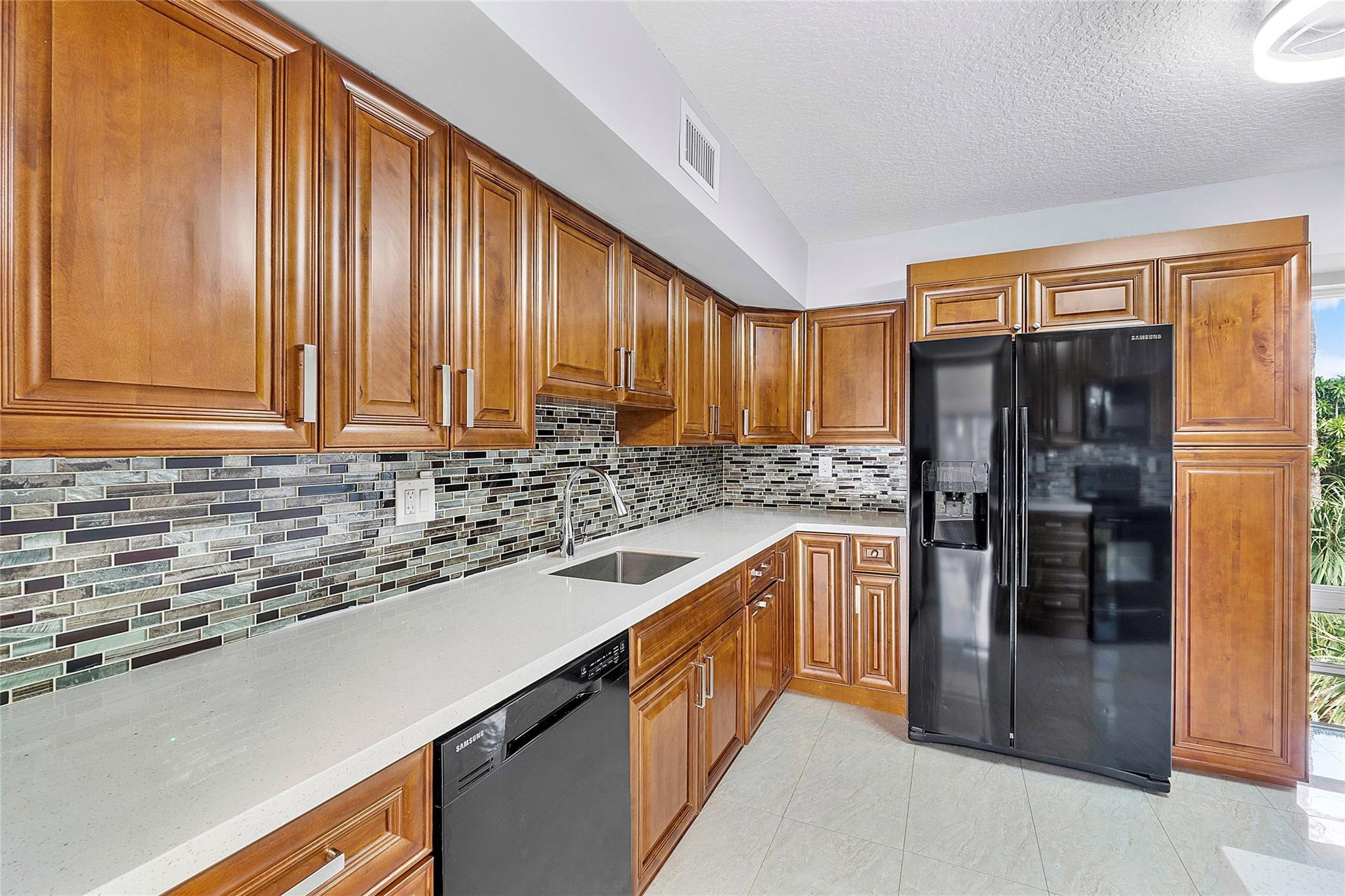 a kitchen with stainless steel appliances granite countertop a refrigerator a sink and a stove