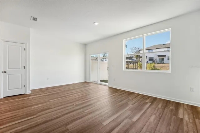 an empty room with wooden floor and windows