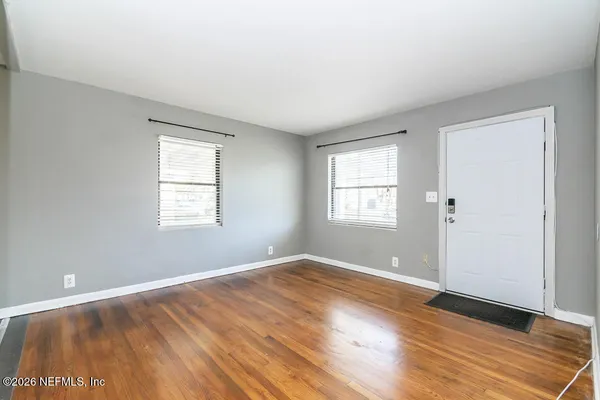 an empty room with wooden floor and windows