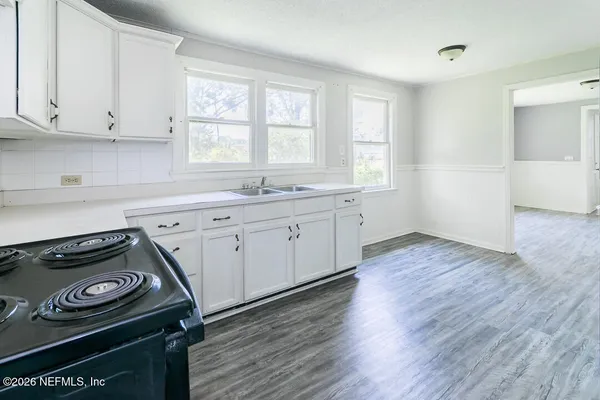 a kitchen with a stove and wooden floor
