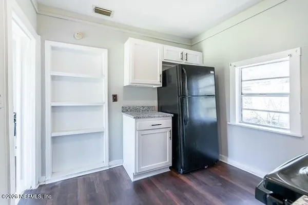 a kitchen with a refrigerator and wooden floor