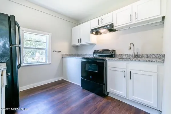 a kitchen with cabinets wooden floor and a window