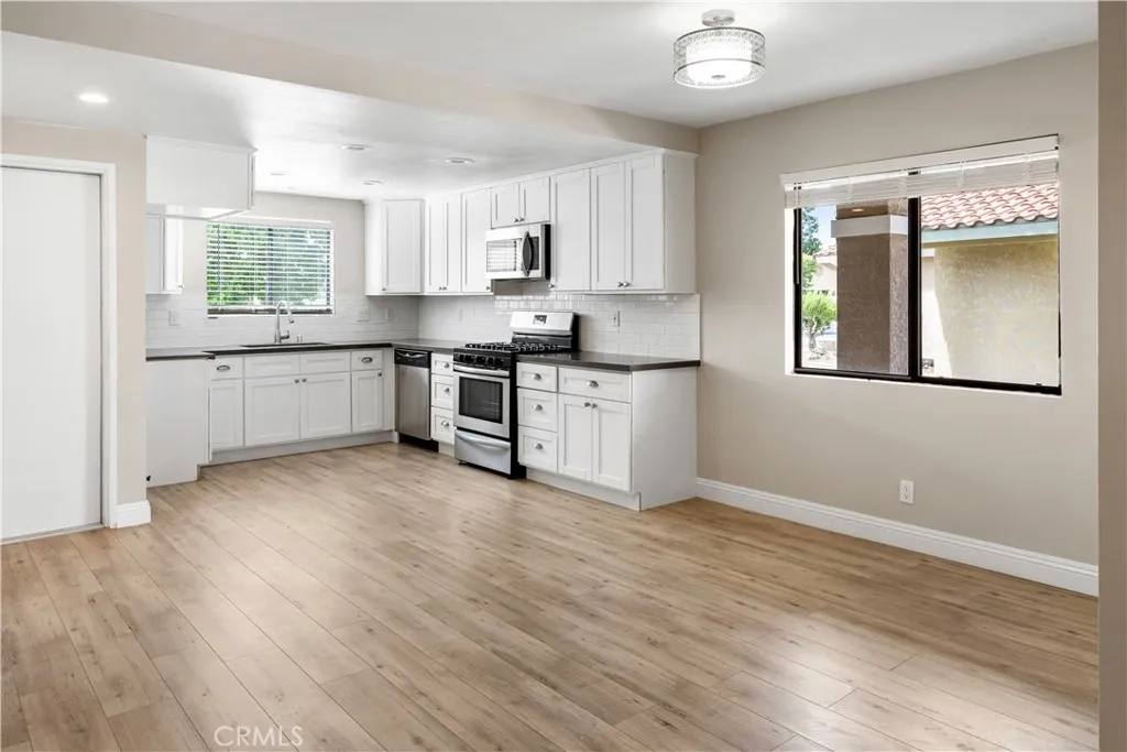 4151 Rexford Drive Hemet, CA 92545 - Photo 3 of 10 a kitchen with granite countertop a stove a sink wooden floor and a window