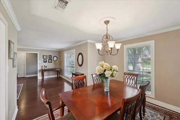 a dining room with furniture a chandelier and wooden floor