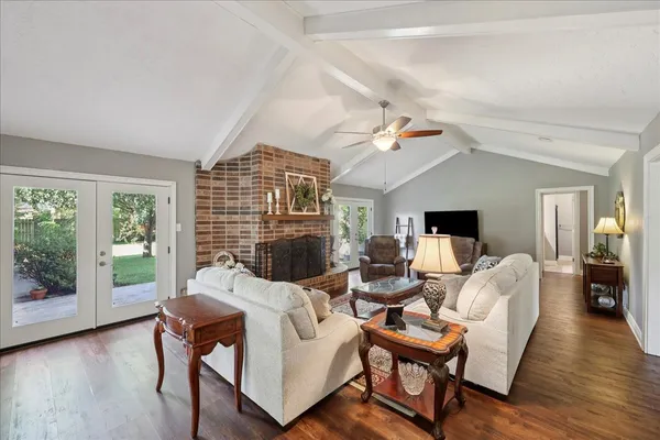 a living room with furniture large windows and wooden floor