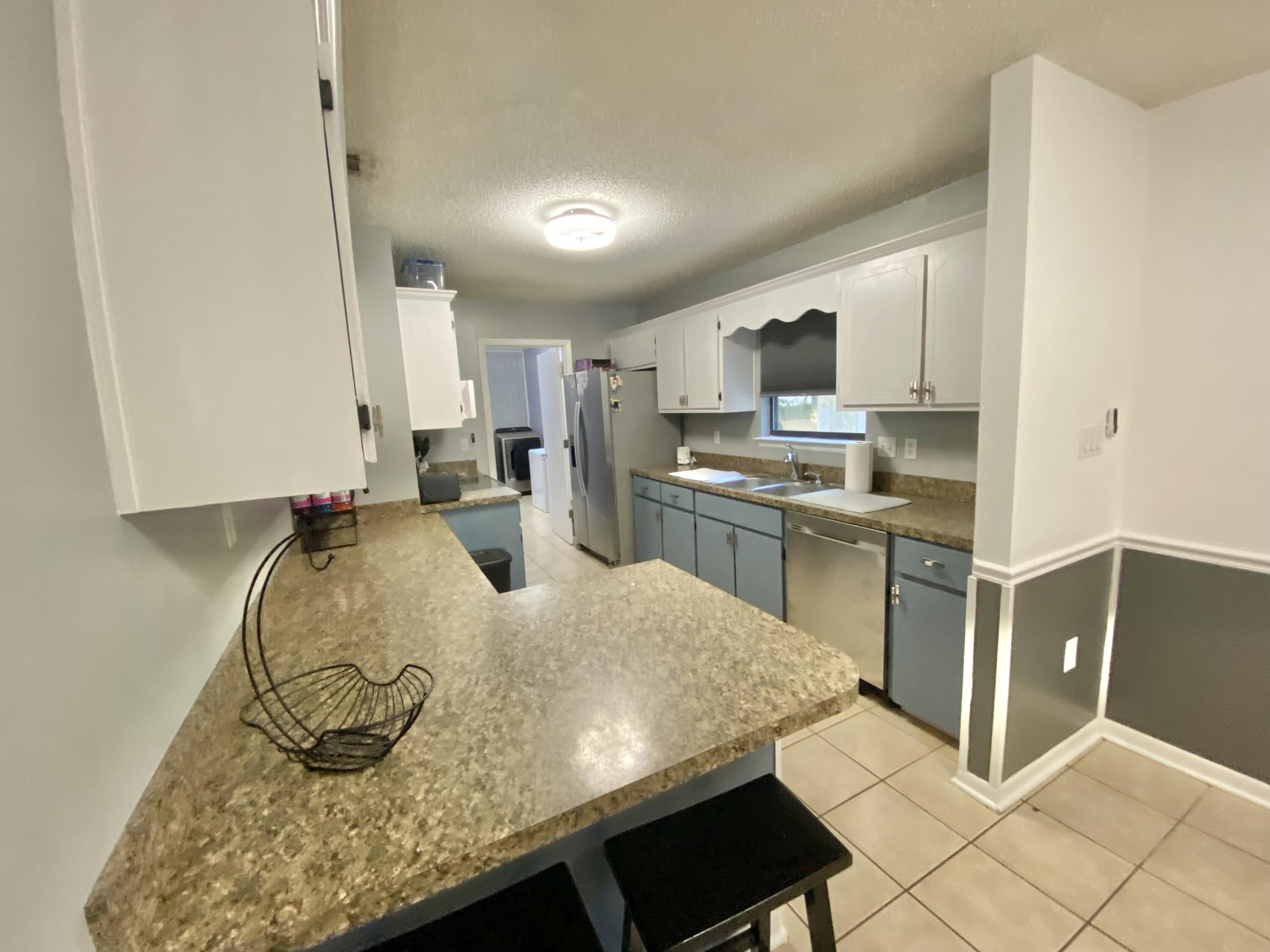 309 Springwood Circle Crestview, FL 32536 - Photo 14 of 44 a kitchen with kitchen island granite countertop a sink cabinets and stainless steel appliances