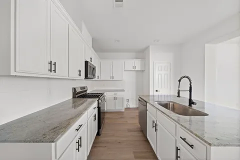 a kitchen with stainless steel appliances granite countertop a sink stove and cabinets