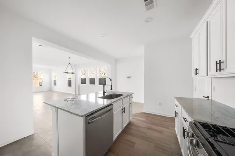 a kitchen with granite countertop a sink stove and cabinets