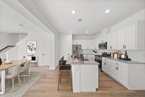a large white kitchen with lots of counter top space a sink appliances and cabinets