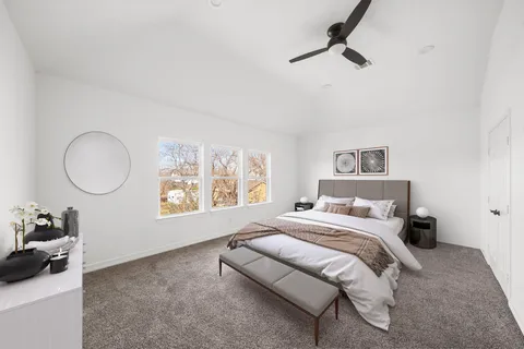 a bedroom with a bed a dresser and windows