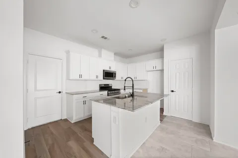 a kitchen with white cabinets and sink