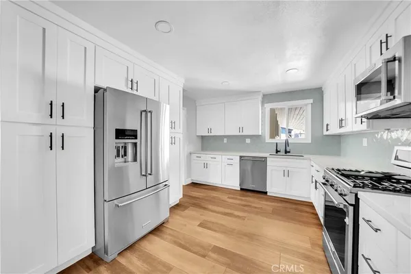 a kitchen with granite countertop white cabinets and stainless steel appliances