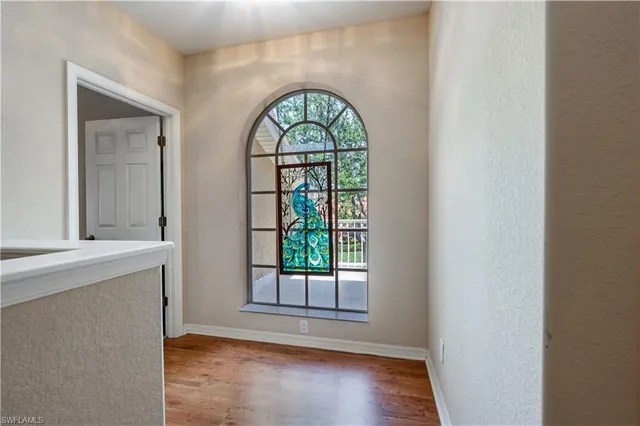 an empty room with wooden floor mirror and windows
