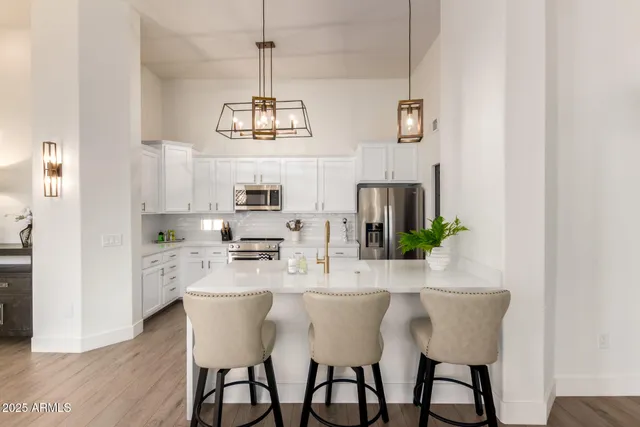 a kitchen with stainless steel appliances a white refrigerator a stove a sink dishwasher a dining table and chairs with wooden floor