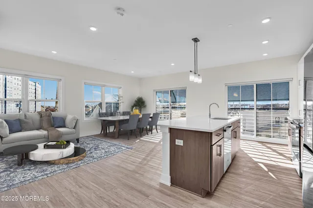 a living room with furniture a wooden floor and kitchen view