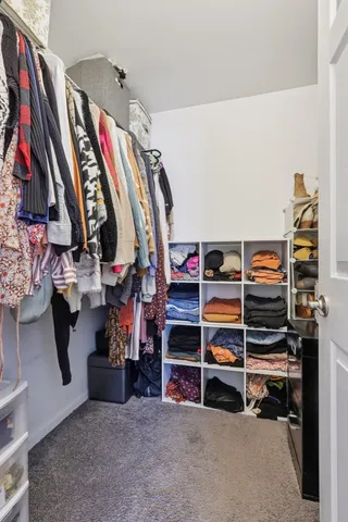 a view of walk in closet with clothes and shoes