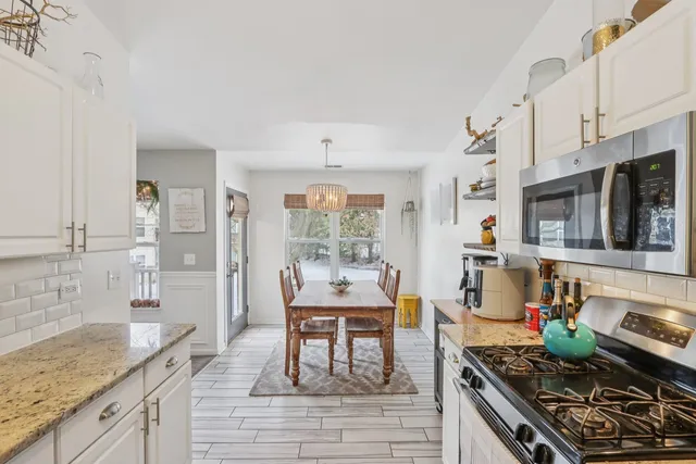 a kitchen with stainless steel appliances granite countertop a stove top oven a sink dishwasher and white cabinets with wooden floor