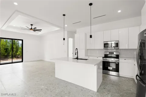 a kitchen with stainless steel appliances granite countertop a sink a stove a refrigerator and a window with wooden floor