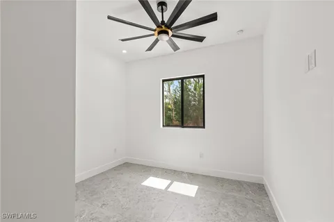 an empty room with a window and a fan