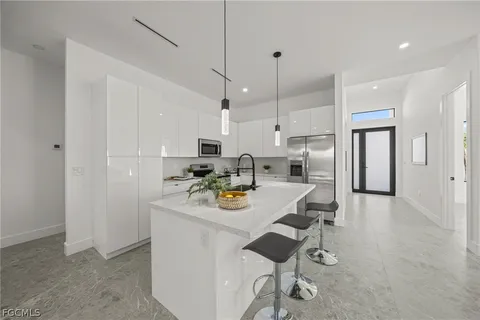 a kitchen with stainless steel appliances granite countertop a sink a stove a refrigerator and white cabinets with wooden floor