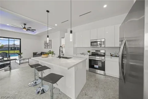 a kitchen with kitchen island a stove a refrigerator a oven a dining table and chairs with a large window