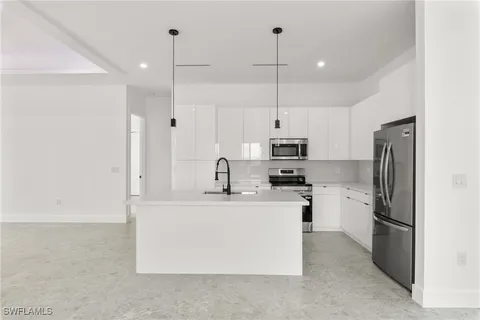 a kitchen with stainless steel appliances a refrigerator a stove a sink and white cabinets