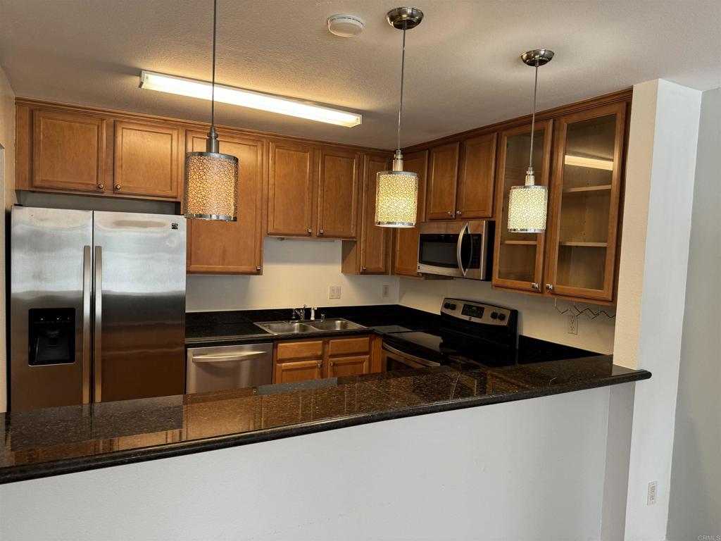 3030 Suncrest Drive, Unit 702 San Diego, CA 92108 - Photo 2 of 17 a kitchen with granite countertop a refrigerator a sink and wooden cabinets
