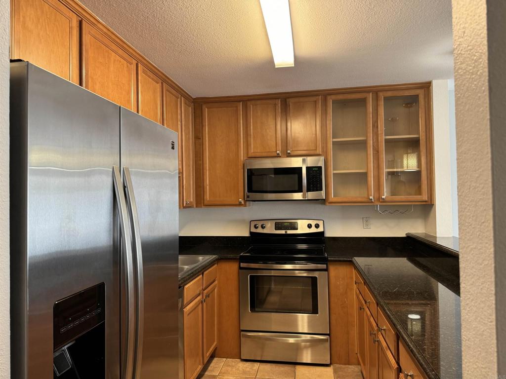 3030 Suncrest Drive, Unit 702 San Diego, CA 92108 - Photo 3 of 17 a kitchen with stainless steel appliances granite countertop a stove a refrigerator and a microwave
