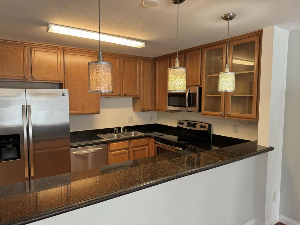 3030 Suncrest Drive, Unit 702 San Diego, CA 92108 - Photo 4 of 17 a kitchen with stainless steel appliances granite countertop a sink a stove and refrigerator