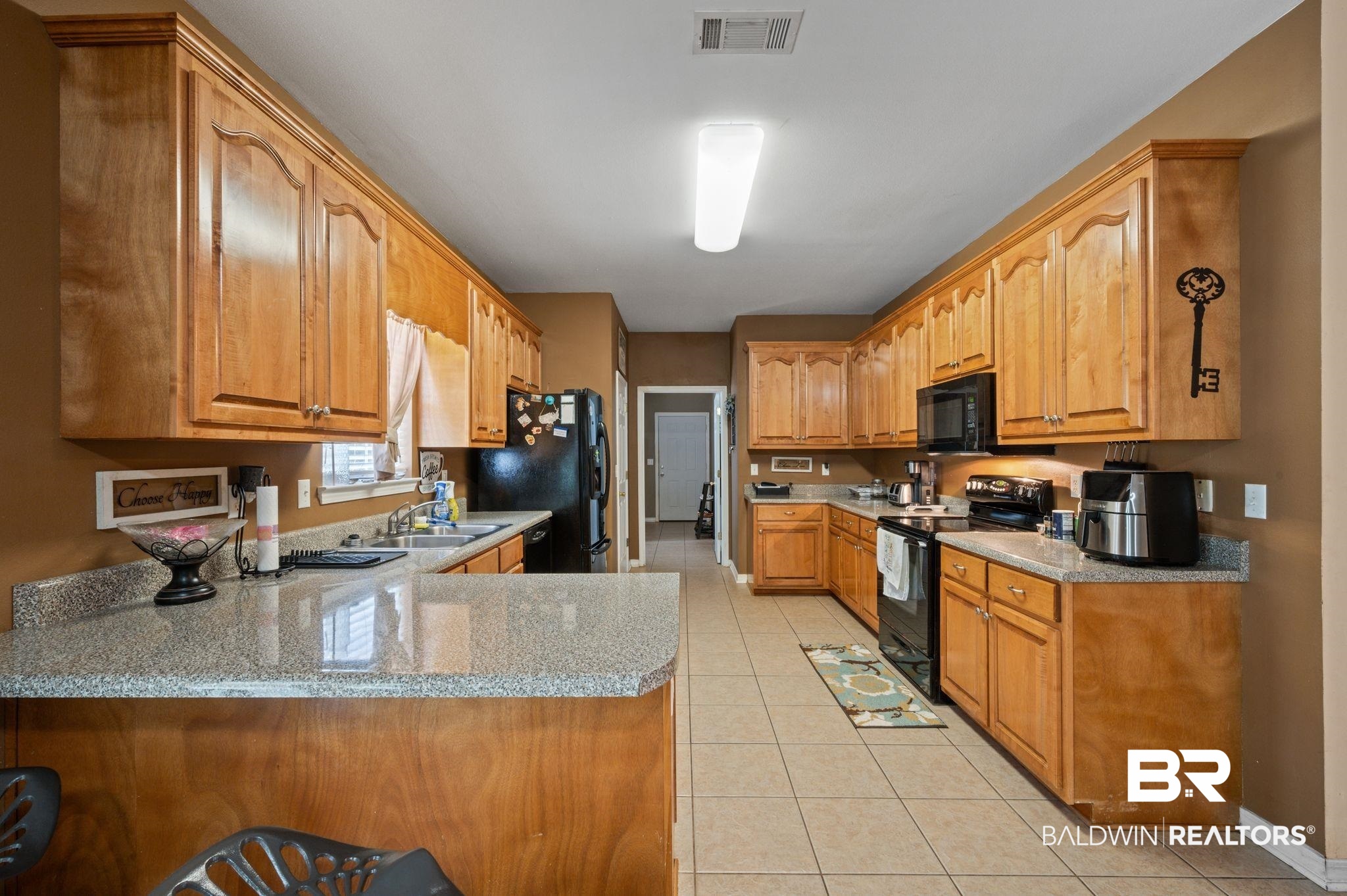 9539 Lakeview Road Bay Minette, AL 36507 - Photo 11 of 45 Kitchen with black appliances, light stone counters, kitchen peninsula, and light tile patterned floors