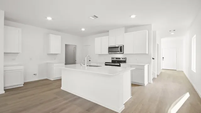 a kitchen with stainless steel appliances a refrigerator sink and white cabinets