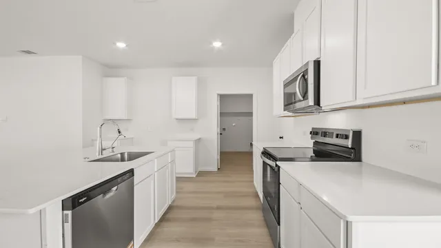 a kitchen with stainless steel appliances granite countertop a sink and dishwasher a stove top oven with wooden floor