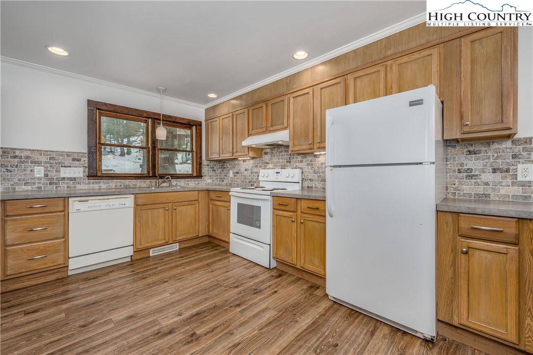 217 Highland Avenue Boone, NC 28607 - Photo 13 of 33 a kitchen with a white refrigerator stove and sink with wooden floor