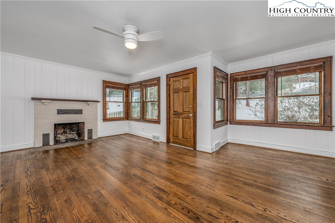 217 Highland Avenue Boone, NC 28607 - Photo 6 of 33 an empty room with wooden floor fireplace and windows