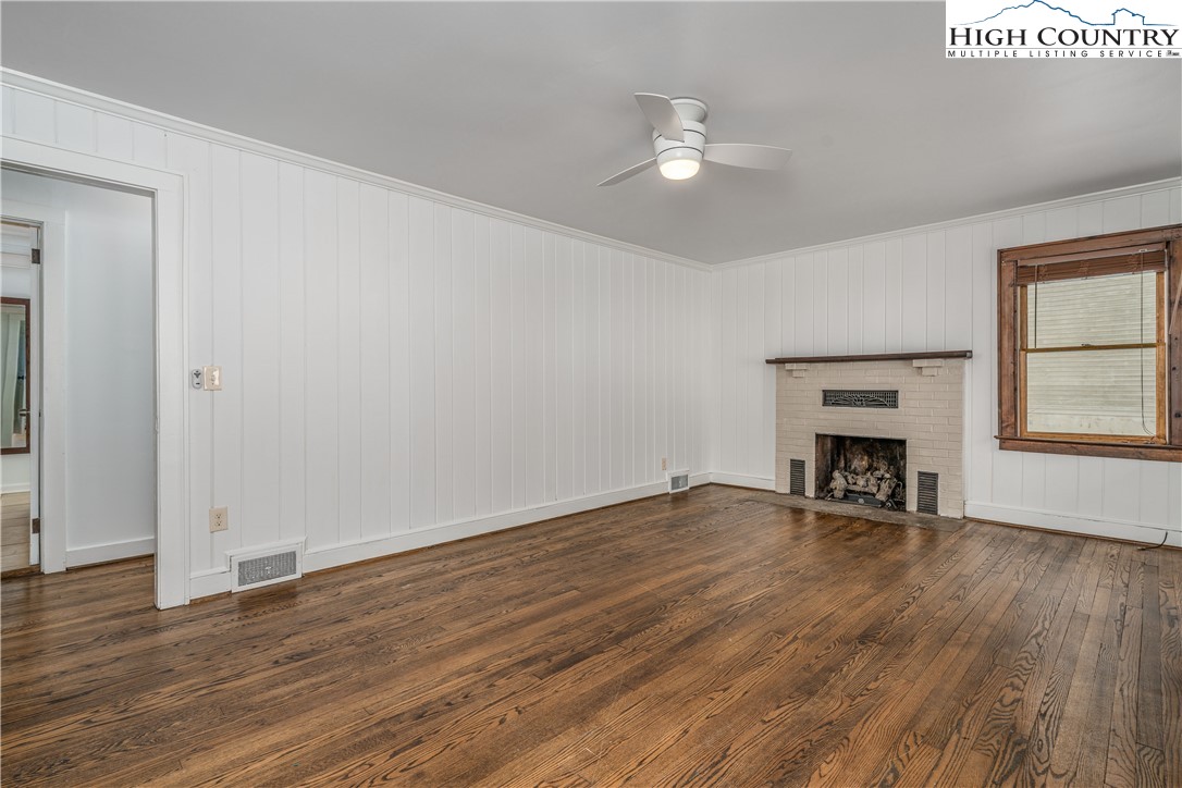 217 Highland Avenue Boone, NC 28607 - Photo 7 of 33 an empty room with wooden floor fireplace and windows