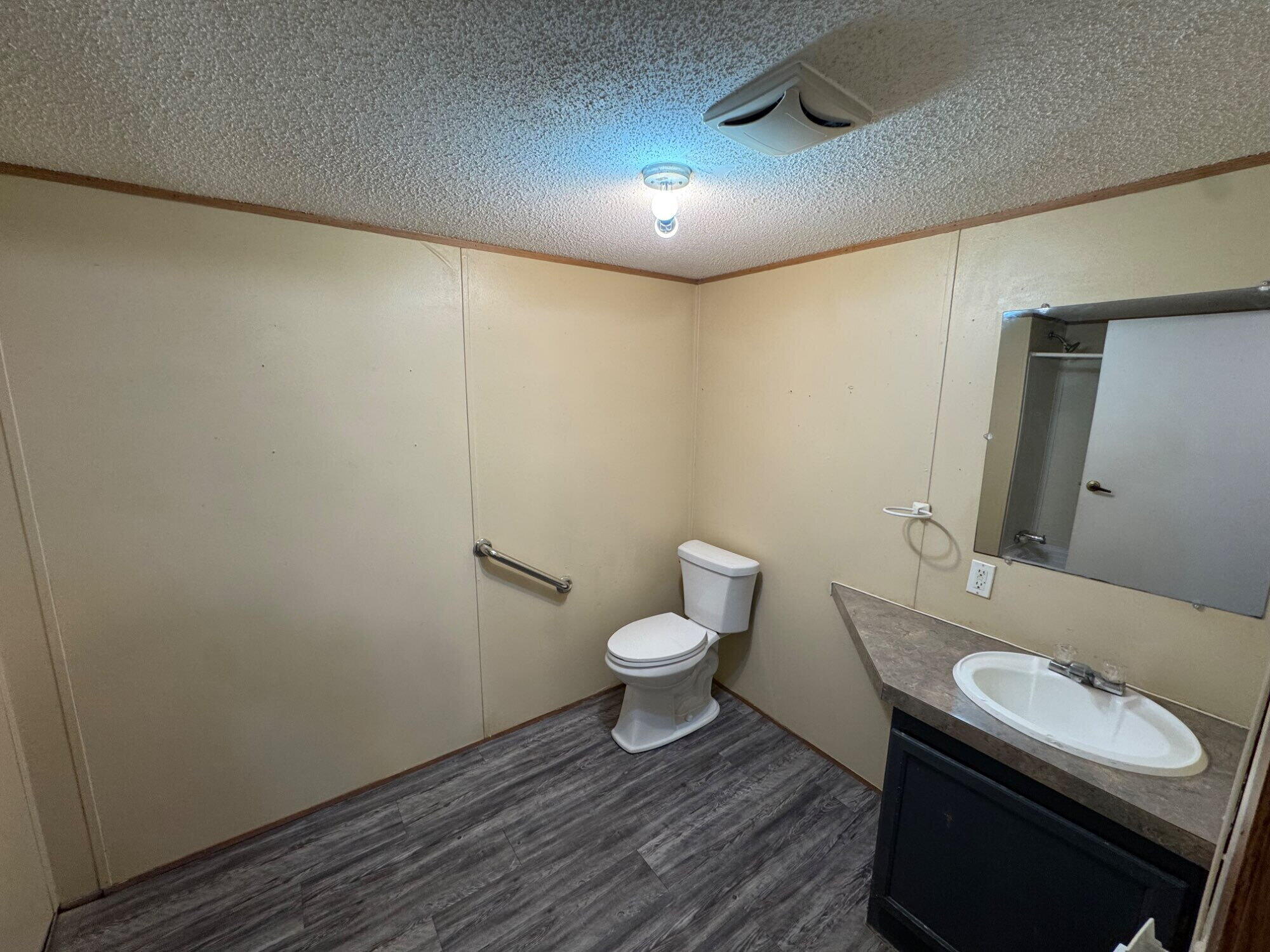 7008 North C R 1500, Unit 20 Shallowater, TX 79363 - Photo 5 of 8 a bathroom with a sink a toilet and a mirror